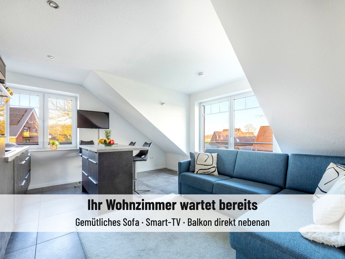 Heller Wohnbereich der Ferienwohnung mit blauem Sofa, Smart-TV und Essbereich